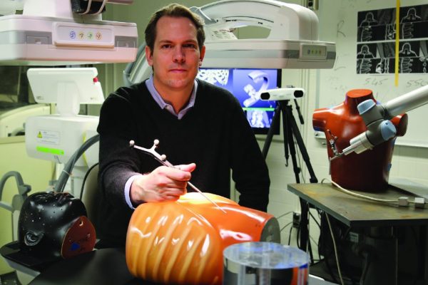 Jeff Siewerdsen poses in a lab with two fake torsos.