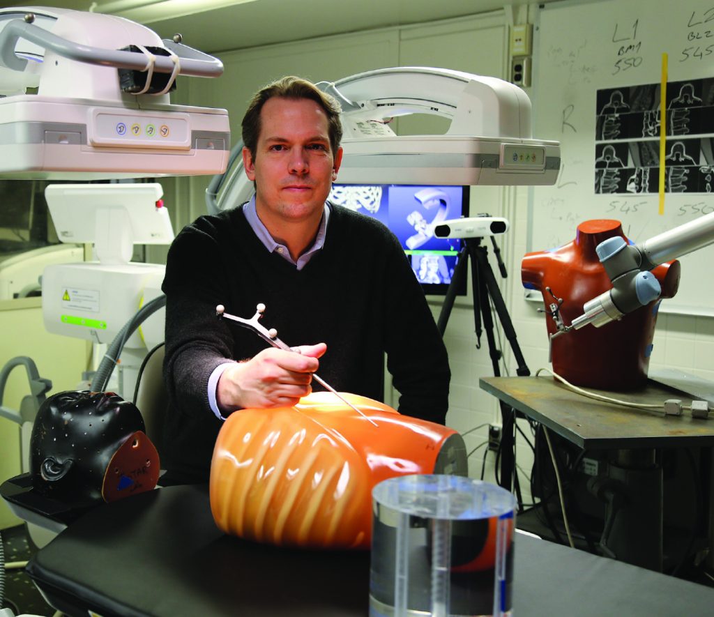 Jeff Siewerdsen poses in a lab with two fake torsos.