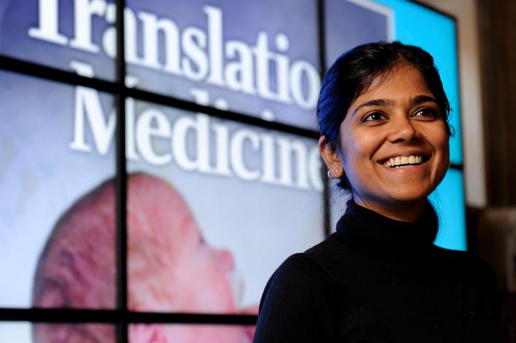 Suchi Saria smiles in front of the cover of Translation Medicine journal.