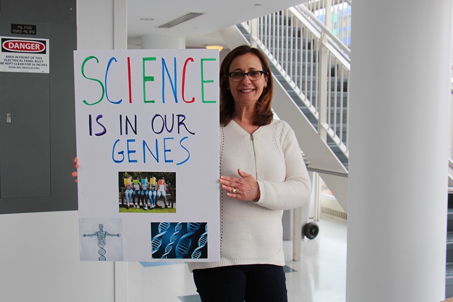 Woman with "Science is in our Genes" poster.