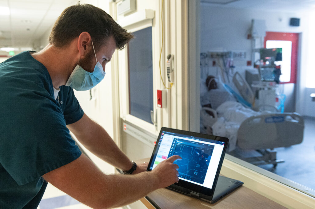 Mechanical Engineering Professor Axel Krieger works in the Johns Hopkins Hospital Bio-Containment Unit to test a robot that adjusts ventilator settings while being controlled via a tablet from outside the patient's room in order to avoid unnecessary patient contact.
