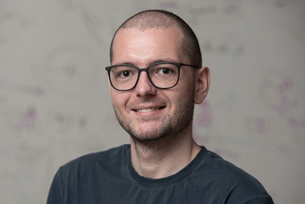 Headshot of Mathias Unberath wearing a gray T-shirt in front of a whiteboard.
