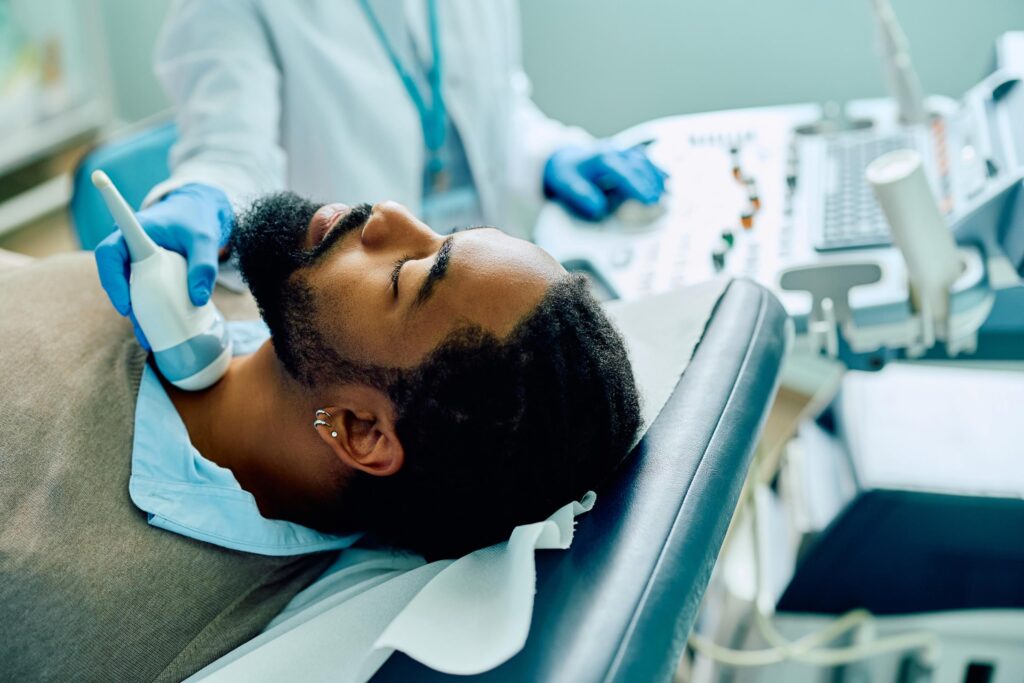 African American male patient during ultrasound thyroid gland examination at the clinic.