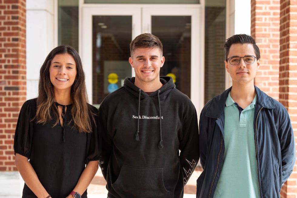 Alejandra Perez Rondon, Nicolás Varela Long, and Héctor Manuel Ramírez Alatorre pose in front of the south entrance of Malone Hall.