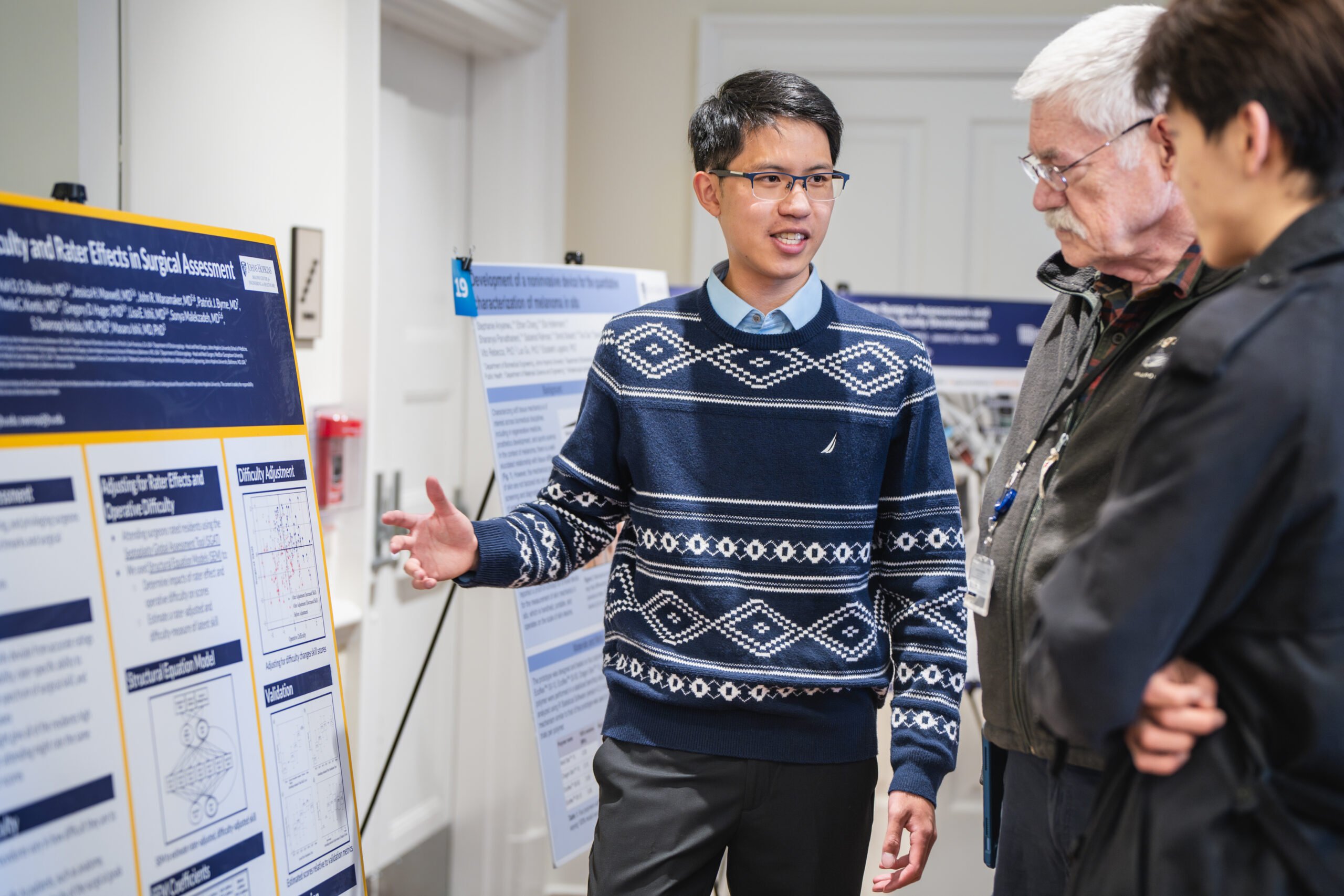 A student presents his poster to Russell H. Taylor and other onlookers.