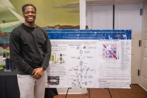 Omobolade Odedoyin stands next to his poster.