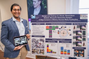 Aabhas Jain holds a tablet next to his poster.