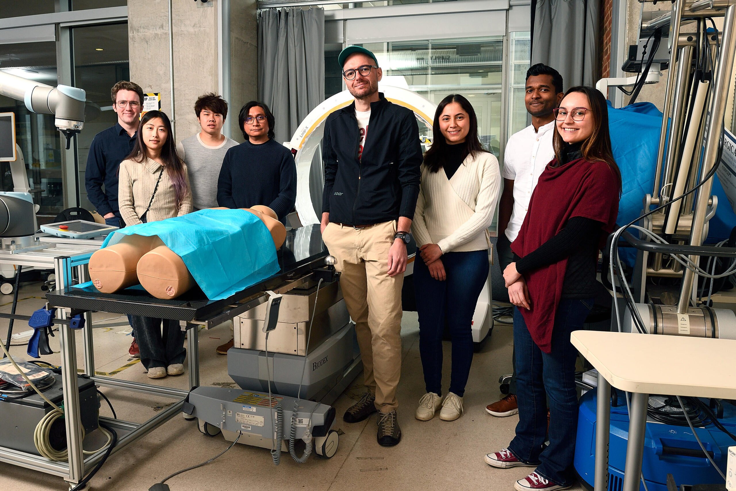 A group of 7 ARCADE Lab members and Mathias Unberath pose in the Mock OR.